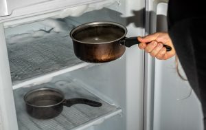 Persona metiendo ollas calientes con agua hirviendo en la nevera (Getty Images)