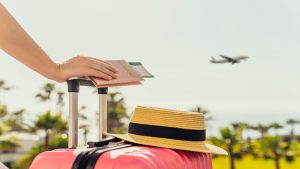 Persona viajera con su maleta y pasaporte (Foto vía Getty Images)